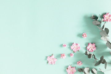 Flowers composition creative. Pink flowers, eucalyptus branches on pastel mint background. Flat lay, top view, copy space