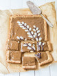 Vertical photo of traditional Polish Easter dessert called mazurek with kajmak (dulce de leche), decorated with willow catkin motive. Baking paper and white wood in the background. Elevated view.  