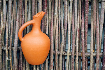 Clay jugs on a decorative fence made of tree branches.