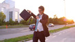 CLOSE UP: Carefree businessman dances along asphalt sidewalk on sunny evening.