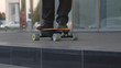 CLOSE UP: Active man in a black suit longboarding through the city after work.