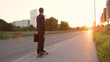 LENS FLARE: Active businessman cruising down the sunlit street on his longboard.