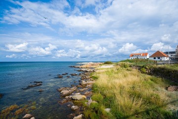 Wall Mural - View of small town on beautiful stony coast of Bornholm island, small plane over the sea, Sandvig, Denmark