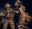 © Fxquadro - Combat conflict, special mission, retreat, call for support. Military medic rescues his wounded teammate carrying him off the battlefield. Studio photo against a dark wall