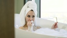 Happy Woman With Bath Towel On Her Head Taking A Bubble Bath, Eating Strawberry And Drinking Champagne At Bathroom. 4K