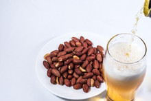 Beer Is Poured Into A Glass And Peanuts In The Saucer. 