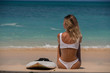 © South House Studio - wonderful back view of surfer girl in white swimsuit sitting near her surfboard,