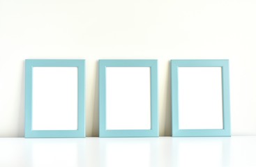 Three blank photo frames on white table, blue frames mockup for kids room interior.