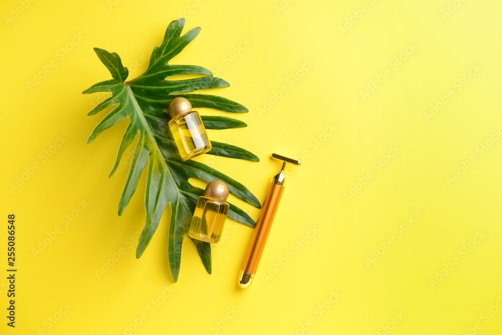 Facial massage tool with essential oil on color background