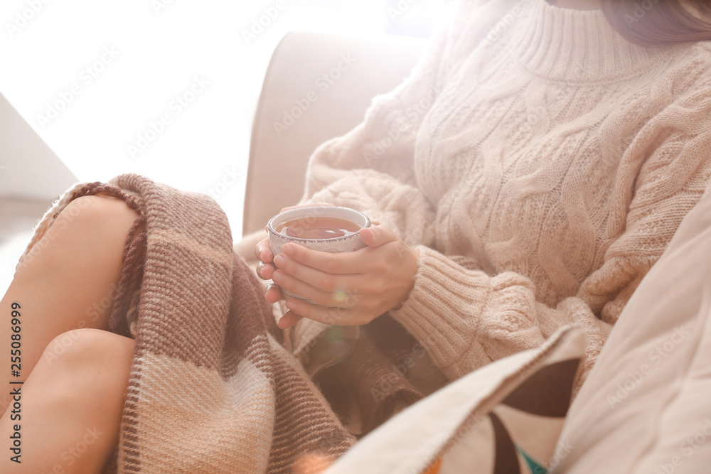 Young woman drinking hot tea at home, closeup