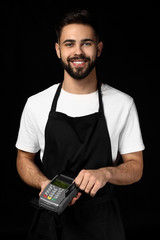 Wall Mural - Handsome waiter with payment terminal on dark background