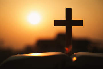  silhouette of cross and bible with the sunset as background, christian concept, spirituality and religion