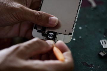 Wall Mural - technician repairing broken mobile phone close-up.Close-up Of A Human Hand Repairing Smartphone With Screwdriver Internal circuits and structural elements of mobile phones