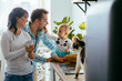 © Iryna - Father, mother , daughter and their cat enjoying morning time together, cooking in the kitchen, playing family lifestyle. Multitasking and husework love animal concept.