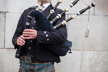 Scottish Bagpiper Dressed In Traditional Dress Performing On The Street