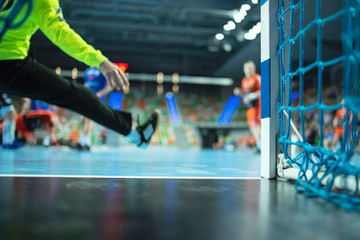 Detail of handball goal post with net and handball match in the background.