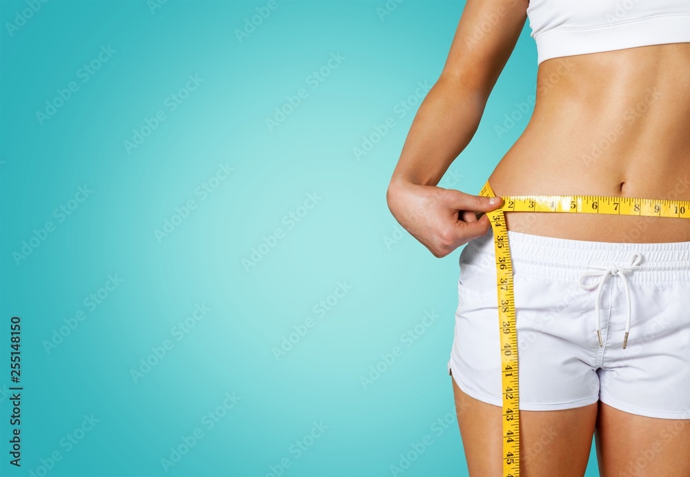 Slim young woman measuring her thin waist - obrazy, fototapety, plakaty 