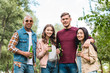 © LIGHTFIELD STUDIOS - cheerful multicultural group of friends holding bottles with beer and looking at camera