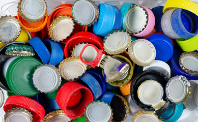 Close up mix of metal and plastic bottles caps in a trash bin .