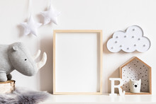 The Modern Scandinavian Newborn Baby Room With Mock Up Photo Frame, Wooden Toy, Plush Rhino And Clouds. Hanging Cotton  White Stars. Minimalistic And Cozy Interior With White Walls.Real Photo.Template