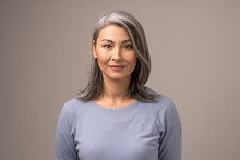 Beautiful Mongolian Woman With Gray Hair On A Gray Background.