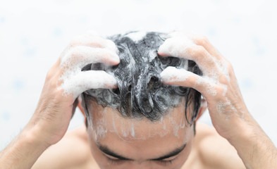 Wall Mural - Closeup young man washing hair with with shampoo in the bathroom, health care concept, selective focus