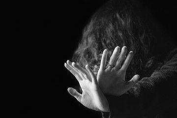 violence against women. black and white portrait of scared and desperate woman, focus on the hands i