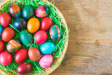 Fototapeta Tulipany - Colorful Easter eggs in basket on old wooden background