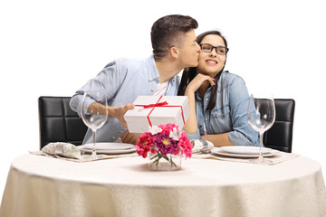 Poster - Young guy sitting at a restaurant table, kissing a girl and holding a present