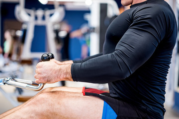 Close up young athlete on rowing machine in gym