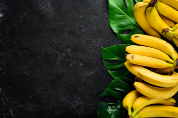 Wall Mural - Fresh yellow bananas on a black stone table. Top view. Free copy space.