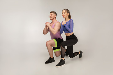 Sporty young couple in trendy colorful sportswear doing lunge on left foot