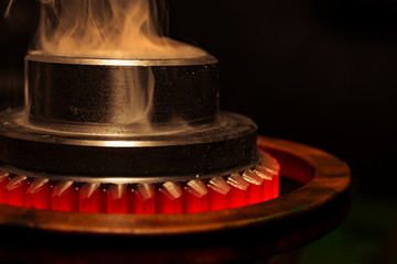 closeup calcining hot metal steel gear parts in a factory induction furnace with smoke