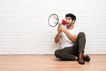 Young man sitting on the floor shouting through a megaphone