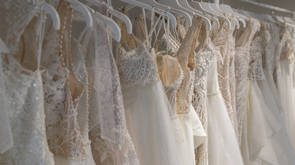 Wedding dresses hang on hangers. Factory of wedding dresses.