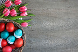 Fototapeta Tulipany - Wielkanocne tło z różowo-białymi tulipanami i kolorowymi pisankami w koszyku