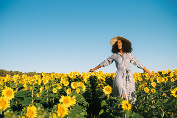 happy young black woman walking in a sunflower field