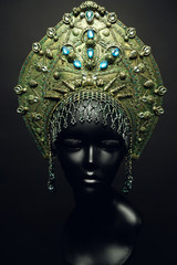 Black head of mannequin in decorated green kokoshnick, dark studio background