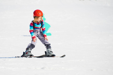 child girl skiing in mountains. active kid with safety helmet and goggles. ski race for young childr