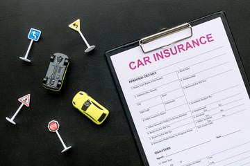 Car insurance concept with form, car toys on black background top view