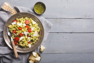 Plate of pasta fusilli with pesto sauce on gray wooden background