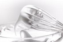 Metal Whisk With Whipped Egg Whites On White Background