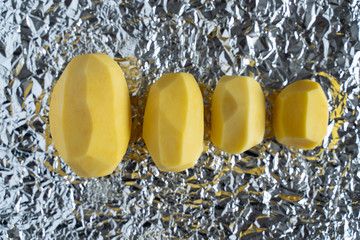 peeled vegetables potatoes onions carrots on the background of the wrinkled silver surface