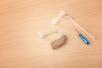 Hearing aid with accessories on wooden background