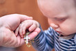 A child takes a rosary from his dad's hand