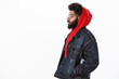 © Cookie Studio - Profile shot of dreamy and thoughtful handsome stylish african american guy in denim jacket over red hoodie, looking down holding hands in pockets as walking and thinking, making important decision