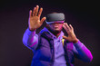© alfa27 - Gaming concept. African casual man in warm seasonal outdoor clothes wearing mobile VR headset enjoying new reality in dark room. Fashion and Innovation gadgets