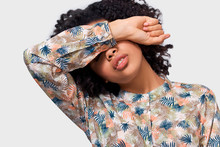 Portrait Of Dark Skinned Young Woman Covering Eyes With Her Arm, Don't Want To See Someone. African American Girl Putting Her Hand Over Forehead Has Tired Feelings. People Emotions Concept
