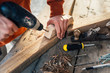 a worker drills a hole in  wooden bar with   drill