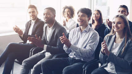 Business audience applauding to speaker at conference